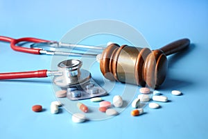 Top view of gavel, stethoscope and pills on white background
