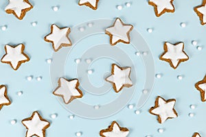 Top view of German star shaped glazed cinnamon Christmas cookies called `Zimtsterne` on light blue background