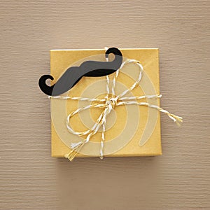 Top view of gift box with mustache over wooden background. Father`s day concept.