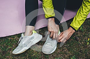 Top view girl exercising outdoors on yoga mat, fitness woman puts sneaker stretching exercises legs training outside