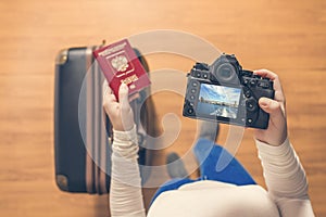 Top view on a girl looking a photos Bridge from Hudson river on her camera standing with suitcase in the airport. The girl returns