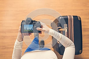 Top view on a girl looking a photos Chicago city on her camera standing with suitcase in the airport. The girl returns home after