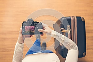 Top view on a girl looking a photos Flowering Sakura on her camera standing with suitcase in the airport. The girl returns home af