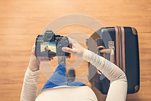 Top view on a girl looking a photos of fresh coconut juice on her camera standing with suitcase in the airport. The girl returns h