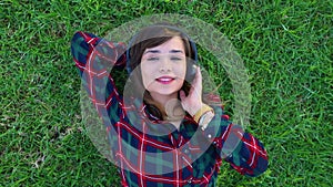 Top view of a girl lying on a meadow listening to music with her headphones