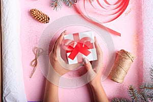 Top view of a girl making a Christmas present on a table background. Handmade present. Creative hobby concept.