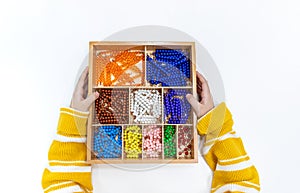 Top view of girls hand is sorting a puzzle of colored plastic beads in montessori school