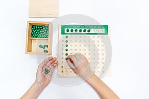 Top view of girls hand is sorting a puzzle of colored plastic beads in montessori school