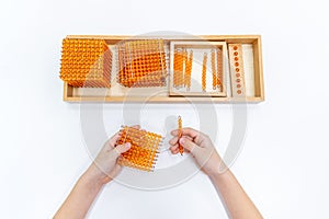 Top view of girls hand is sorting a puzzle of colored plastic beads in montessori school