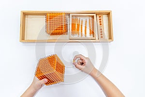 Top view of girls hand is sorting a puzzle of colored plastic beads in montessori school
