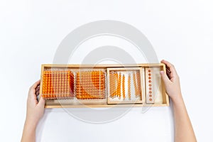 Top view of girls hand is sorting a puzzle of colored plastic beads in montessori school