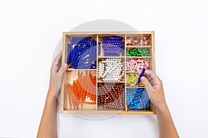 Top view of girls hand is sorting a puzzle of colored plastic beads in montessori school