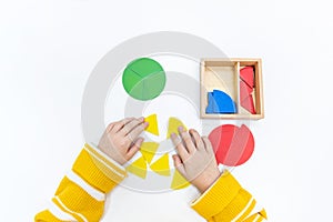 Top view of girls hand is sorting a puzzle of colored wooden geometric shapes in montessori school