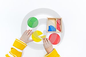 Top view of girls hand is sorting a puzzle of colored wooden geometric shapes in montessori school