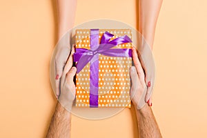 Top view of giving and receiving a gift on colorful background. Present in male and female hands. Love concept. Close up