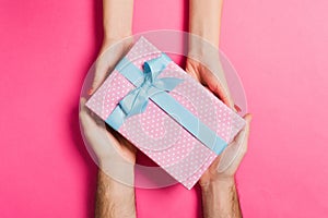 Top view of giving and receiving a gift on colorful background. Present in male and female hands. Love concept. Close up