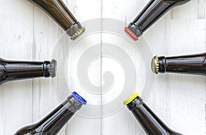 Top view of glass beer bottles with colorful caps on a wooden surface