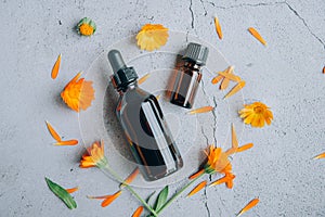 Top view of glass bottles of calendula essential oil with fresh marigold.