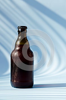 Top view of glass brown beer bottle, glass of beer against blue background close up. Food lifestyle. Alcoholic drink production