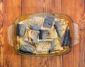 Baked mackerel in glass casserole pan on old rustic table