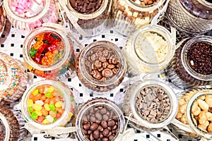 Top view glass containers with various additives to ice cream. Choice of filler - candies, nuts, jelly sweets, chocolate, coconut,