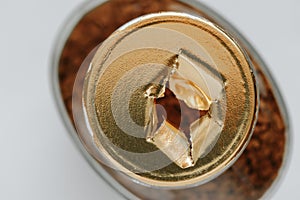 Top view of a glass jar of coffee without a lid, the gold-colored label is torn, the integrity of the packaging is broken, the