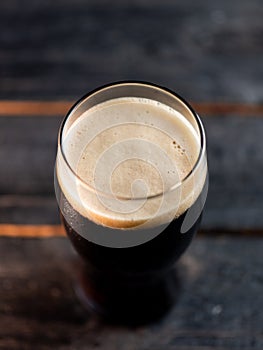 Top view a glass of porter beer on a dark pub table