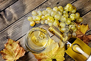 Top view of a glass of wine and fresh bunch of white grapes on a