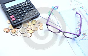 Top view a glasses,pencil, money, calculator and chart or graph on office desk table.Finance and business concept.