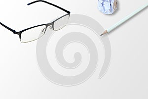 Top view of glasses, white pencil and white crumpled paper ball place on gray floor.