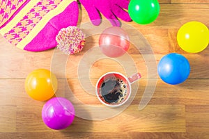 Top view gloves, Silk hat, colored balls and a cup of coffee on wood table. In the winter.