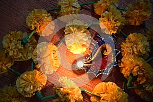 Top view of glowing lit colorful conch shaped diya around marigold on occasion of Diwali festival