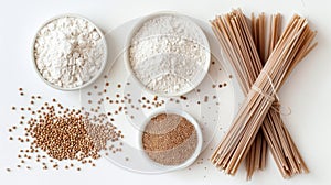 Top view of gluten-free ingredients with bowls of buckwheat flour, whole grains, and a bundle of soba noodles on a white