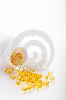 Top view of Gold fish oil scattered from pill bottle isolated for good health on white background. Supplementary food
