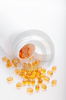 Top view of Gold fish oil scattered from pill bottle isolated for good health on white background. Supplementary food