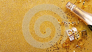 Top view. Gold glitter background with craft gifts, champagne bottle and christmas tinsel