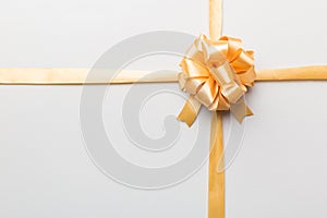 Top view of gold ribbon rolled and yellowbow isolated on colored background. Flat lay with copy space