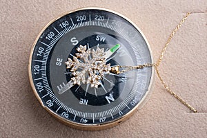 Top view of a gold snowflake necklace on a compass