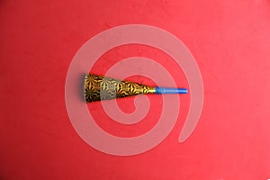 Top view of a golden cardboard party trumpet on a red background