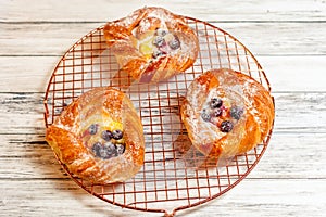 Top view of golden chese danish pasties with blackberries and powder sugar