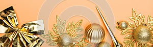 Top view of golden Christmas decor on orange background, panoramic shot.