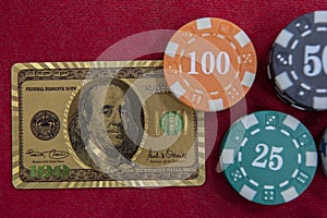 Top view of golden 100 dollar playing cards next to stacks of chips on red felt table