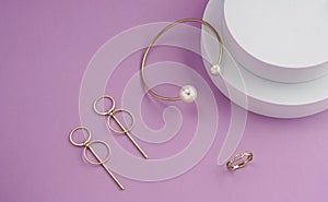 Top view of golden jewelries on round white podium on purple background with copy space