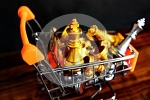 Top view golden king chess with chess pieces in small shopping cart om retro wood floor isolate on black