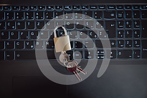 Top view of a golden padlock with keys in it placed on laptop computer keyboard