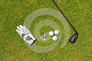 Top view of golf equipment on green grass on a golf course. Flat lay of golf club, balls, glove, tees