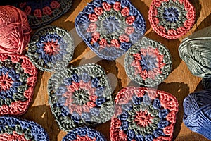 Top view of granny squares with skeins of cotton on wooden surfa