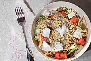 Top view of a greek salad bowl with cracked wheat, tomatoes, lettuce and feta chesse