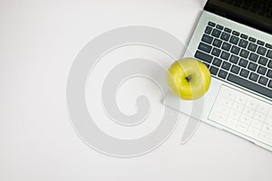 Top view of green apple on laptop keyboard isolated