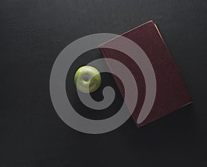 Top view Green apple with old book on black wood background. Sch